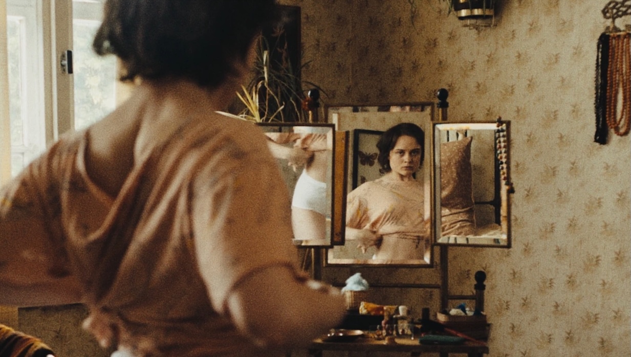 Image 5-16-25 at 1102 AM | Filmmaker Magazine A young woman adjusts her crop top in front of a mirror.
